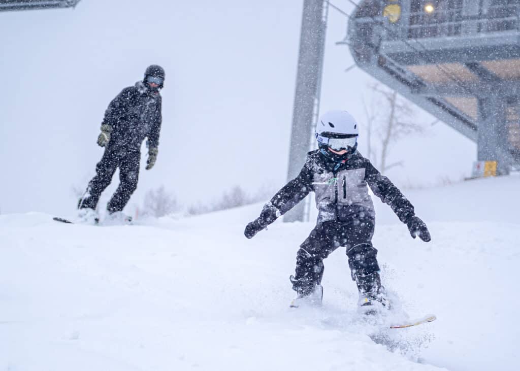 Child snowboarding with his father at Nordic Valley Ski Resort