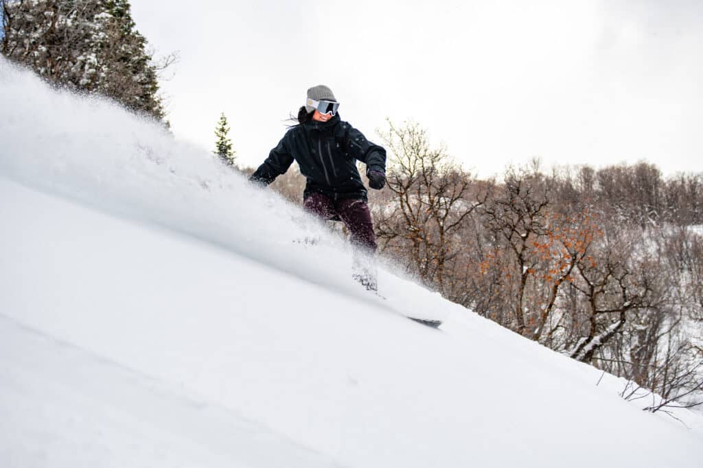 A person riding through deep snow. Trees seen in the background.